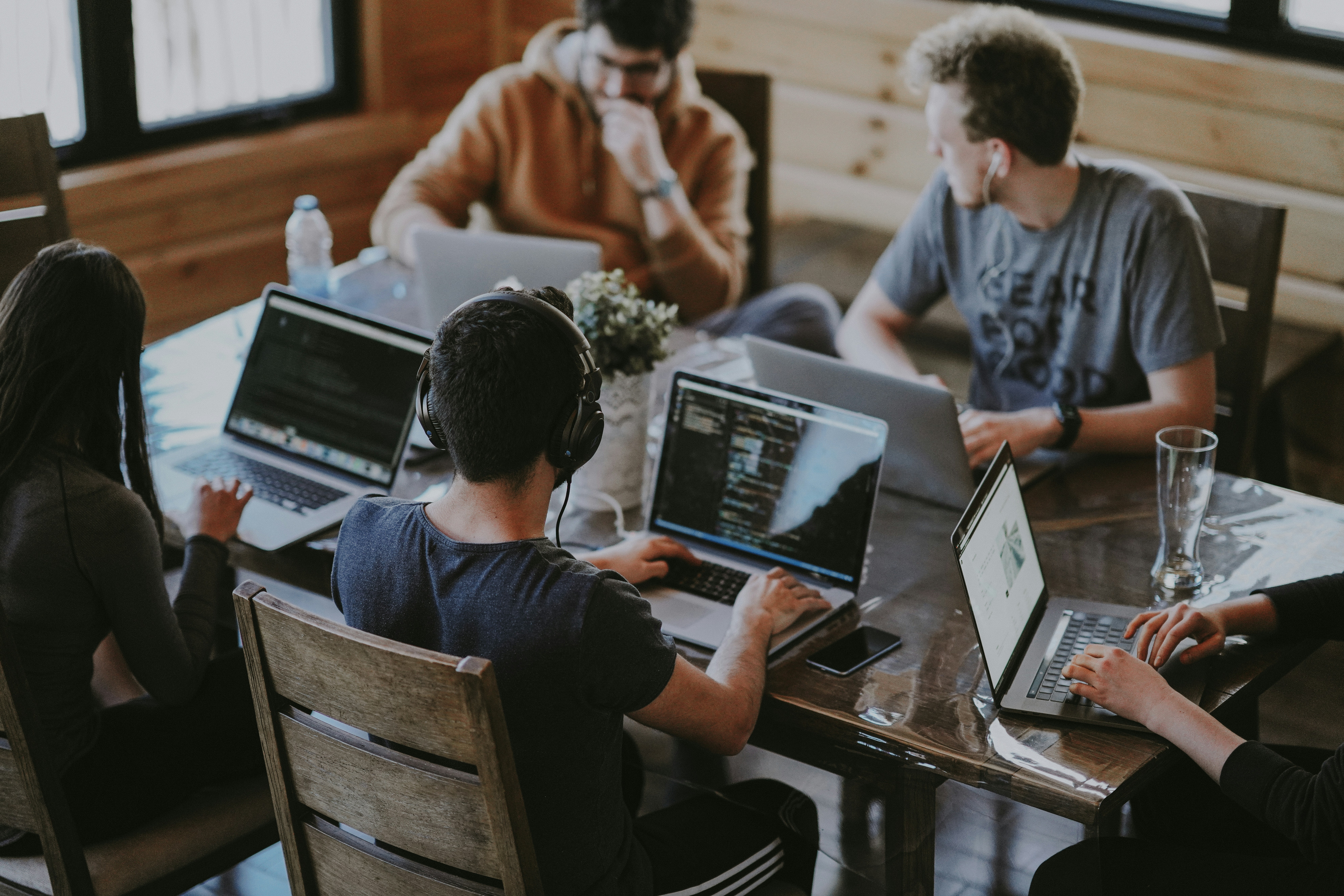 Five college students talking together at a table with their computers open.